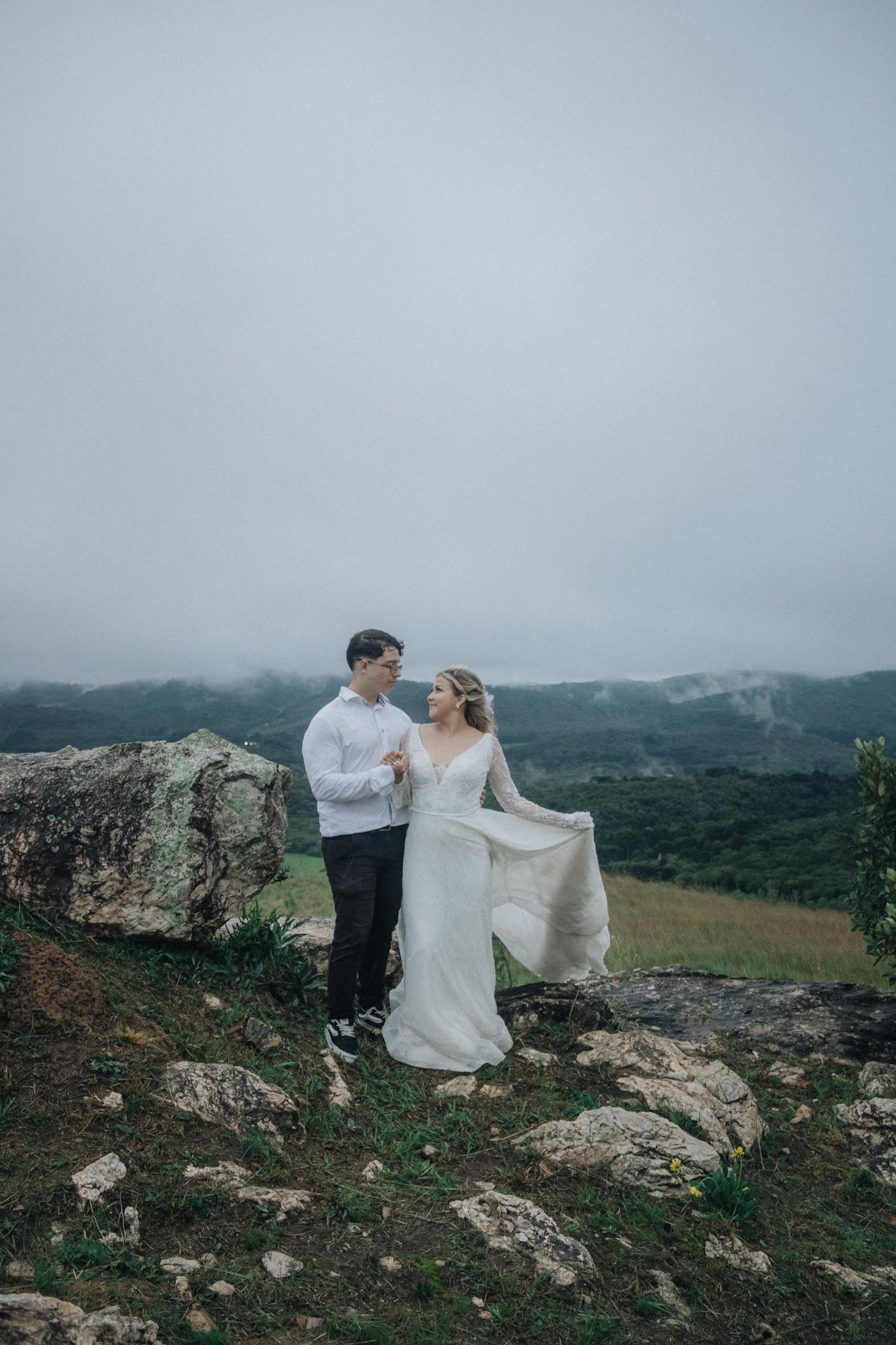 A couple enjoying a serene moment on a foggy hilltop, surrounded by nature's beauty.