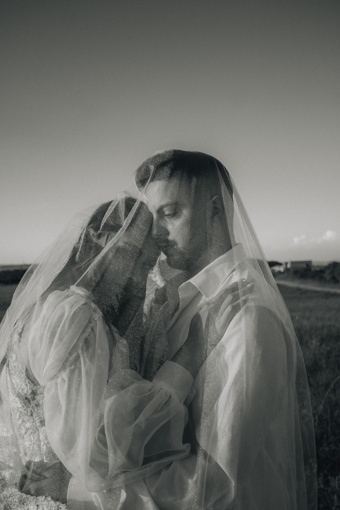 A tender black and white wedding photo of a couple in a serene outdoor setting.